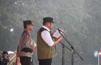 Meski diguyur hujan deras, Kapolda Sumsel Irjen Pol Andi Rian R Djajadi bersama Gubernur Sumatera Selatan H Herman Deru memimpin Apel Gelar Pasukan Operasi Lilin Musi 2025 di halaman Griya Agung Palembang, Jumat (19/12/2025).