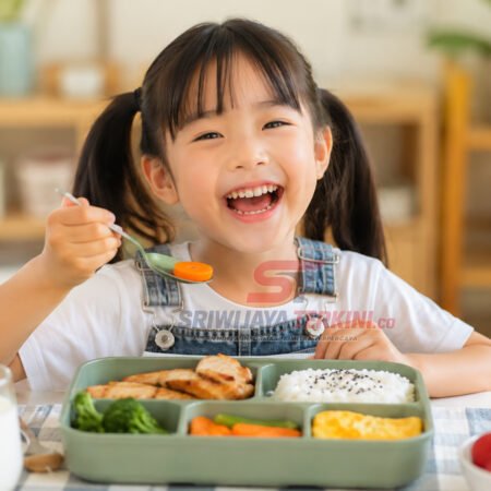 5 Menu Makan Siang Anak yang Bikin Semangat Beraktivitas Seharian, Nomor 3 Favorit Si Kecil! Seorang anak menikmati menu makan siang sehat berisi nasi, ayam, sayuran, telur, dan buah di meja makan dengan suasana ceria. (Foto: dok sriwijayaterkini.co)